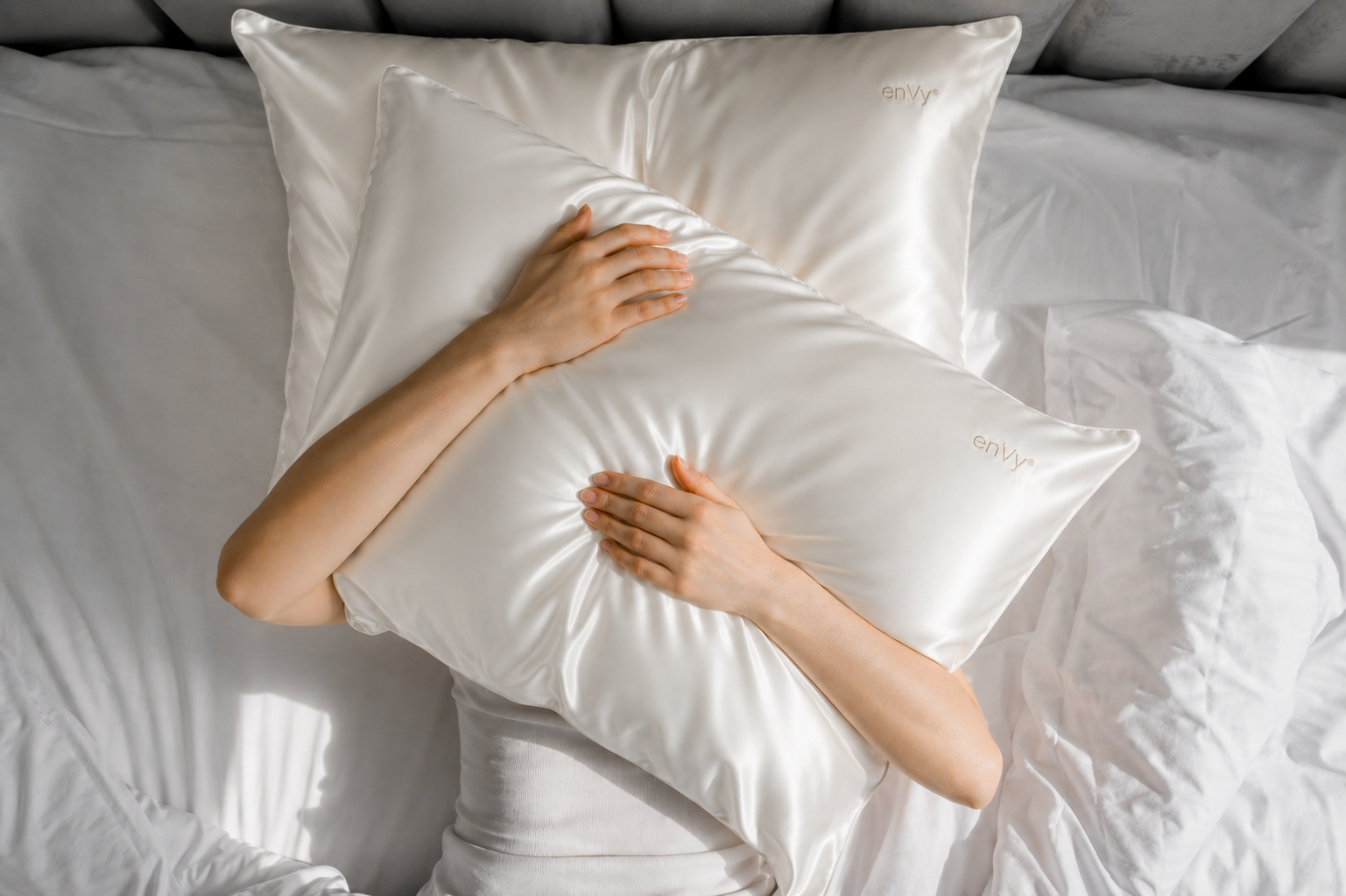 Person holding their favourite pillow with the enVy® COPPER infused SILK pillowcase on it